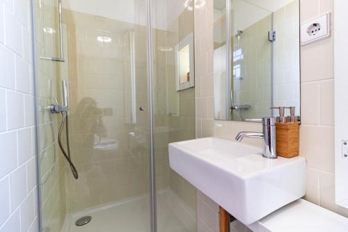 a white bathroom with a sink and a shower at Cozy Studio Apartment in Porto