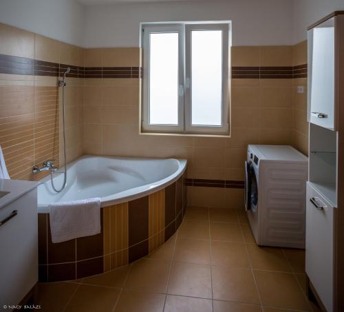 a bath tub in a bathroom with a window at IKON apartman in Hajdúszoboszló