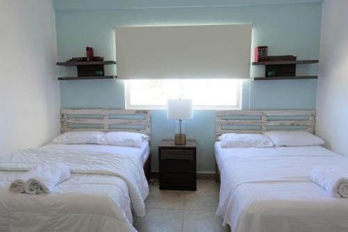 two twin beds in a room with a window at Ideal tu casa fuera de casa in Cancún