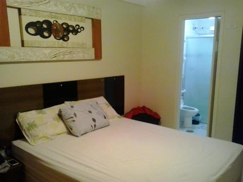 a bedroom with a bed with a white sheets and pillows at Apartamento Enseada, Guarujá, 3 dorms, 3 banhs, 8 pessoas, 250 metros da praia, 2 sacadas, 2 vagas de garagem in Guarujá
