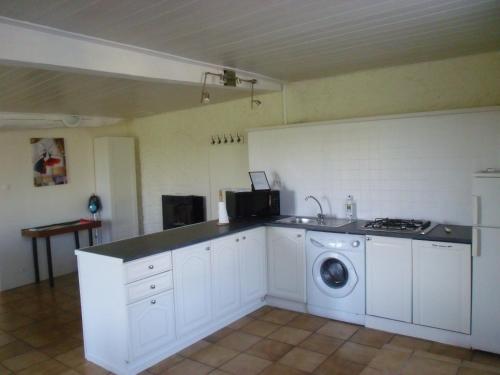 a white kitchen with a washing machine in it at La Petite Grange in Lorignac