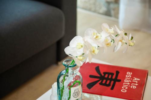 a glass bottle with flowers in it next to a book at Palacio del Agua Apartamentos in Úbeda