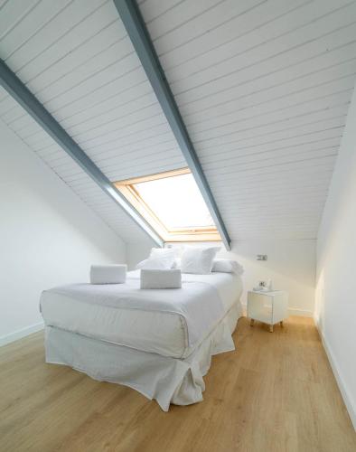 a bedroom with a large white bed with a skylight at Palacio del Agua Apartamentos in Úbeda