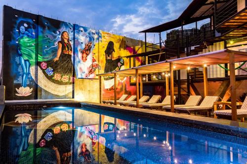 a swimming pool with a mural on the side of a building at Cabane Container Hotel - ADULTS ONLY in Puerto Escondido