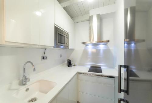 een witte keuken met een wastafel en een magnetron bij Palacio del Agua Apartamentos in Úbeda