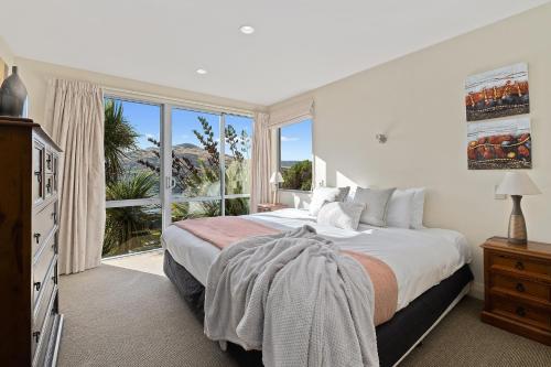 a bedroom with a bed and a large window at Oriwa View in Queenstown