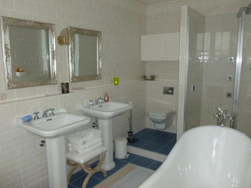 a bathroom with two sinks and a tub and a toilet at La chambre au Château in Pernant
