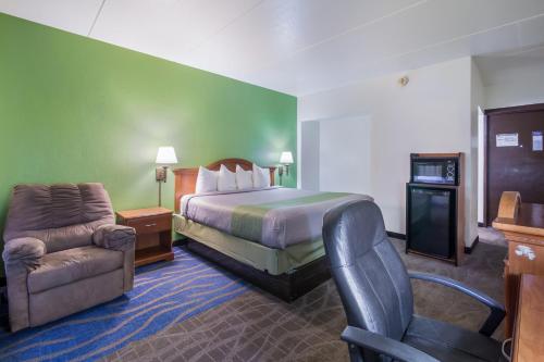 um quarto de hotel com uma cama e uma cadeira em Badlands Inn & Suites em Dickinson