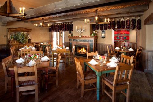 Hotel Chimayo de Santa Fe في سانتا فيه: مطعم بطاولات وكراسي خشبية ومدفأة