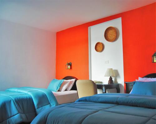 a room with orange walls and blue beds at Ikala Quito Boutique Hotel in Quito