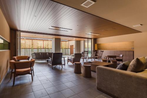 a living room with a couch and tables and chairs at Oike Hotel in Fujikawaguchiko