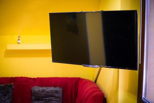 una TV a schermo piatto appesa a una parete gialla di Apartment Jacobs a Bled