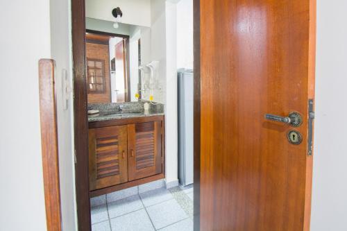 a bathroom with a wooden door and a sink at Pousada Casuarina Geribá in Búzios