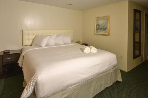 a bedroom with a large white bed with towels on it at Cape Sands Inn in West Yarmouth