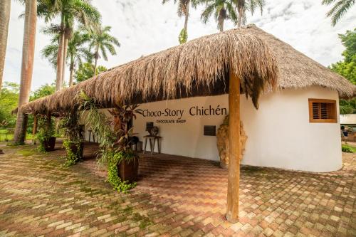 a small white building with a straw roof at Mayaland Hotel & Bungalows in Chichén-Itzá