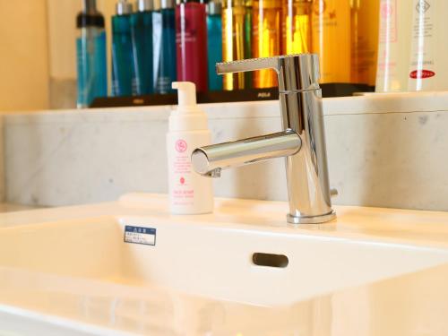 a bathroom sink with a white soap bottle on it at ホテルファインシエル鳥取砂丘店 - 大人専用 in Tottori