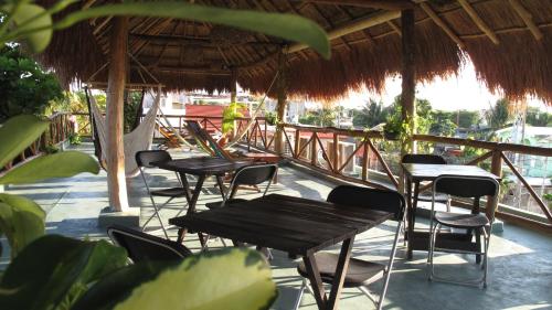 a group of tables and chairs under a straw roof at Casa Almendro in Tulum