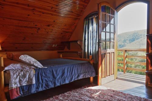 ein Schlafzimmer mit einem Bett und einem großen Fenster in der Unterkunft Pousada Dona Felicidade in Cunha