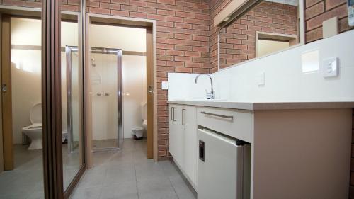 a bathroom with a sink and a brick wall at Ashleigh Court Motor Inn in Mulwala