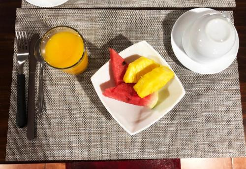 a plate of fruit on a table with a glass of orange juice at Casa Jungle Monteverde B&B in Monteverde Costa Rica