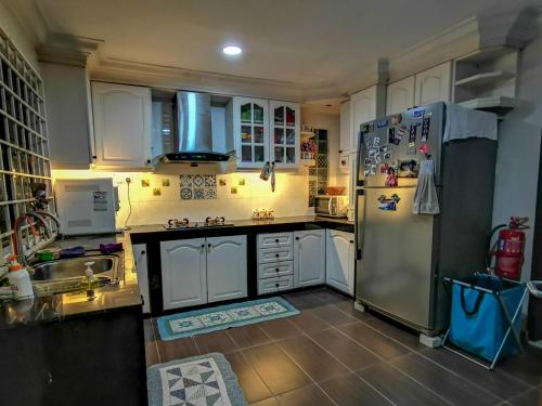 een keuken met witte kasten en een koelkast bij RIA Homestay in Johor Bahru