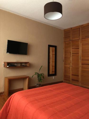 a bedroom with a red bed and a flat screen tv at Cozy Private Room in Mexico City