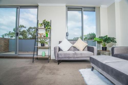 a living room with a couch and some windows at Designed Home of Ultimate Convenience In Gordon in Pymble