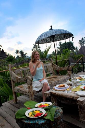 a woman sitting on a chair under an umbrella at Ayurvedagram Bali in Ubud