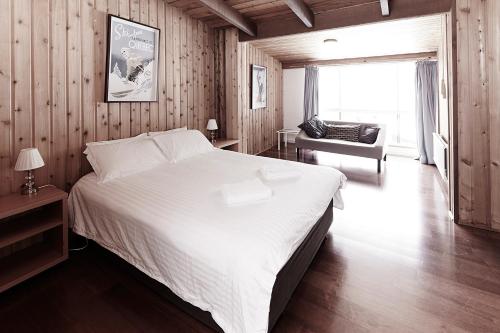 een slaapkamer met een groot wit bed en een stoel bij Moose 10 in Mount Buller