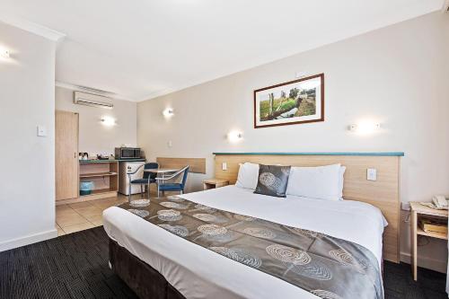 een hotelkamer met een groot bed en een keuken bij Welcome Inn 277 in Adelaide