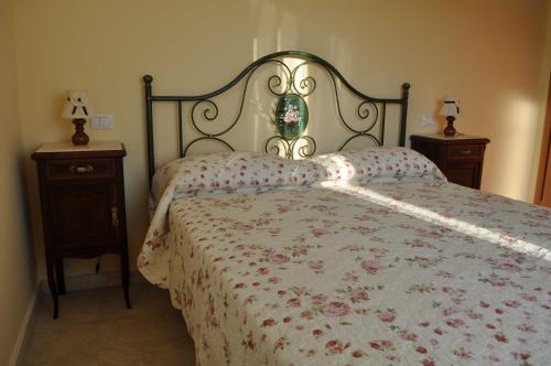 LapedonaにあるAgriturismo Monte Maggioのベッドルーム1室(花柄のベッドカバー、ナイトスタンド付)