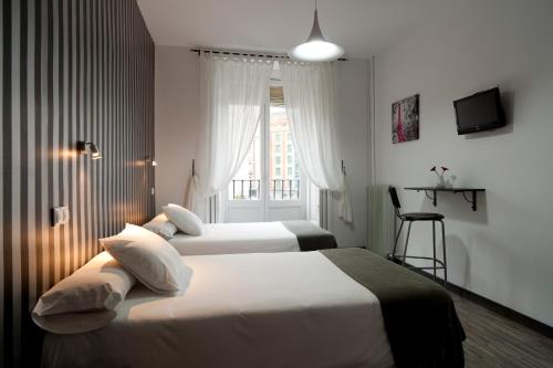 two beds in a hotel room with a window at Hostal Gala Madrid in Madrid