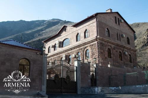 a large brick building with a fence in front of a mountain at Armenia in Nerkʼin Giratʼagh