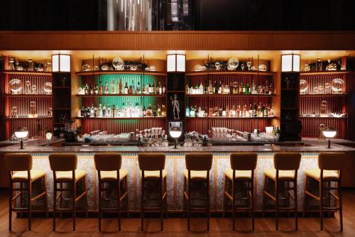 a bar with stools in a room with alcohol shelves at Eaton HK in Hong Kong