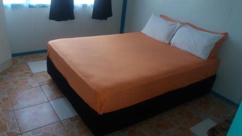 łóżko w pokoju z pomarańczową kołdrą w obiekcie Aitutaki Budget Accommodation w mieście Amuri