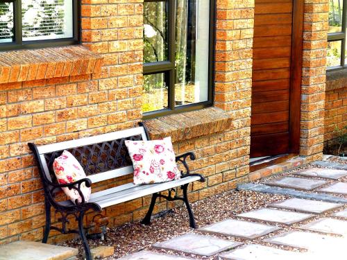 a bench with two pillows sitting next to a brick wall at Cape Goodness in Bellville