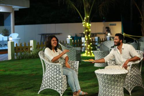 a man and a woman sitting in chairs with a plate of food at JVK Park Hotel in Cochin