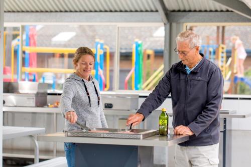 a man and a woman preparing food in a kitchen at Ingenia Holidays Torquay Australia in Torquay