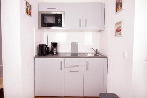 a white kitchen with a sink and a microwave at Ferienwohnung BECKENDORF in Losheim
