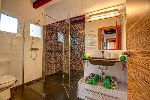 a bathroom with a shower and a sink and a toilet at Villa Sargantana Negra in Binibeca