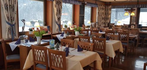a dining room with tables and chairs and windows at Landhaus Eickler in Baiersbronn