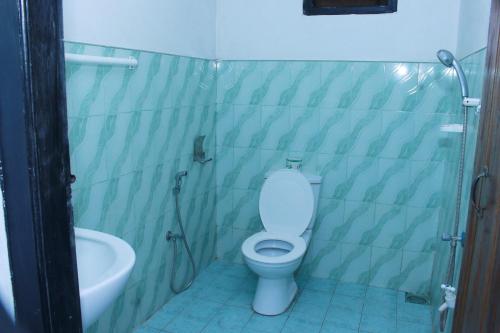 a bathroom with a toilet and a bath tub at Akki's Hostel in Trincomalee