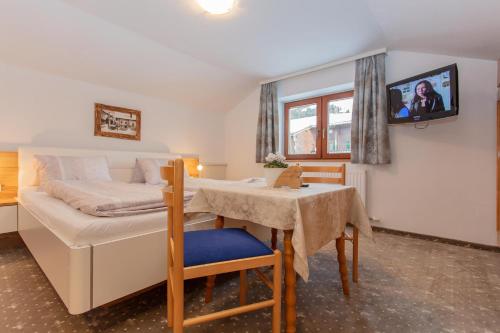 a bedroom with a bed and a table and a tv at Gästehaus Rosi in Fieberbrunn