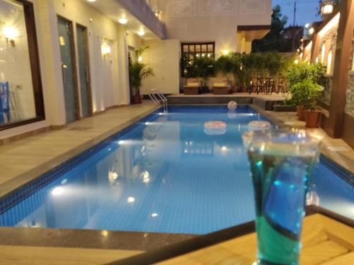 a swimming pool with a drink on a table at Laxmi Palace Heritage Boutique Hotel in Jaipur