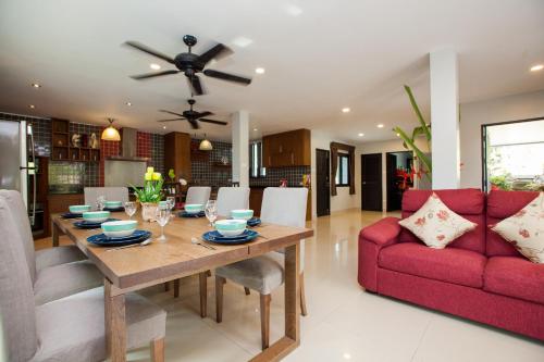 a dining room with a table and a red couch at Baan Santhiya Private Pool Villas - Free Tuk-Tuk Service to the Beach! in Ao Nang Beach