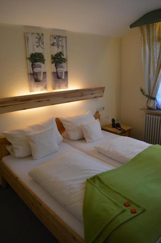 a large bed with white sheets and pillows at Landhaus Eickler in Baiersbronn