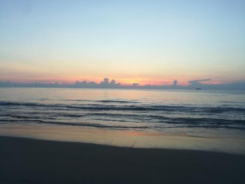 a beach with the sun setting in the ocean at Akki's Hostel in Trincomalee