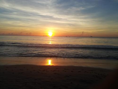 a sunset on the beach with a reflection in the sand at Akki's Hostel in Trincomalee