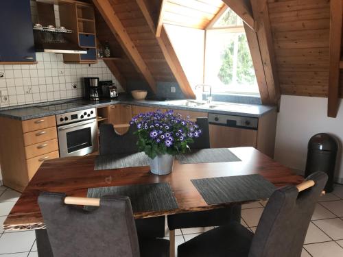 una cocina con una mesa de madera con flores púrpuras. en Gasthof Schweizerhof, en Villingen-Schwenningen