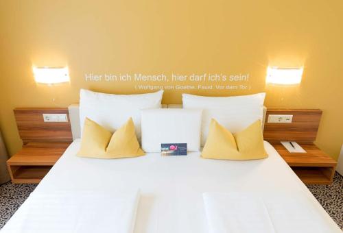 a bed with white sheets and yellow pillows at Hotel Süd Graz in Graz